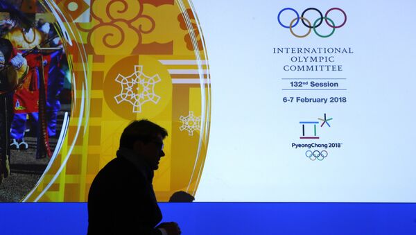 Član Međunarodnog olimpijskog komiteta prolazi pored displeja sa logom MOK-a na Zimskim olimpijskim igrama u Pjongčangu - Sputnik Srbija