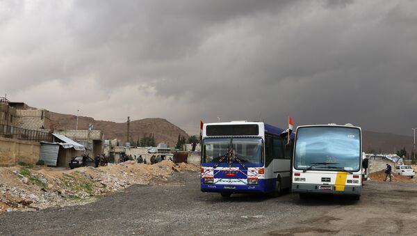 Pripadnici sirijskih vladinih snaga stoje pored autobusa na kontrolnom punktu u predgrađu Damaska tokom operacije izvlačenja skoro 400.000 stanovnika Istočne Gute da napuste ovu enklavu - Sputnik Srbija