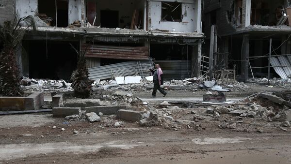 Сиријац пролази поред уништених зграда у граду Хаза који држе терористи - Sputnik Србија