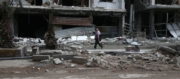 Сиријац пролази поред уништених зграда у граду Хаза који држе терористи - Sputnik Србија