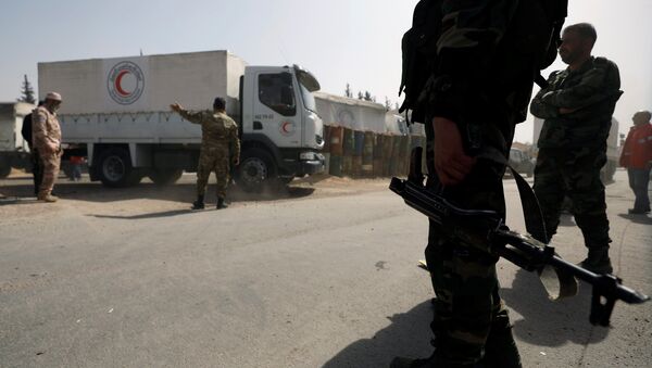 Сиријски војници поред камиона сиријског Црвеног полумесеца који носе помоћ у предграђу Дамаска - Sputnik Србија