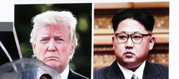 Žena prolazi pored displeja na kome su prikazani američki predsednik Donald Tramp i severnokorejski lider Kim Džong Un - Sputnik Srbija