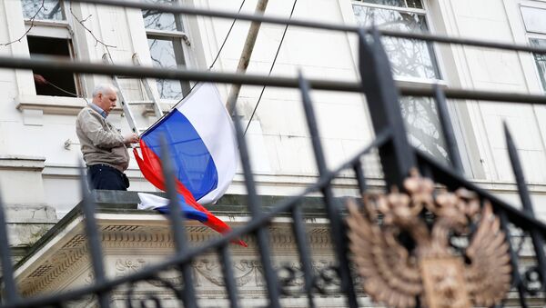 Čovek skida zastavu Rusije sa zgrade ruske diplomatske misije u Londonu - Sputnik Srbija