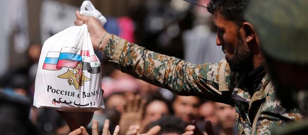 Сиријски војник дели становништву помоћ из Руисје - Sputnik Србија