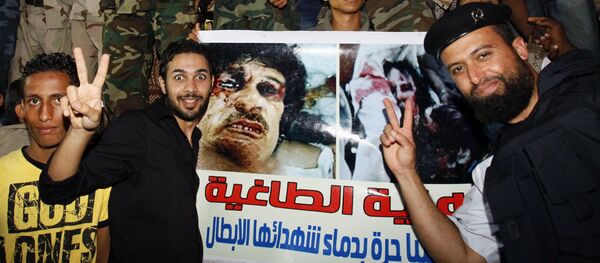 Побуњеници из Либије славе поред транспарента са фотографијом убијеног Муамера Гадафија. - Sputnik Србија