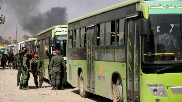 Pripadnici sirijske vojske stoje pored autobusa kojima se pripadnici terorista i članovi njihovih porodica evakuišu iz Haraste - Sputnik Srbija