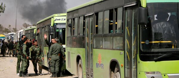 Pripadnici sirijske vojske stoje pored autobusa kojima se pripadnici terorista i članovi njihovih porodica evakuišu iz Haraste - Sputnik Srbija