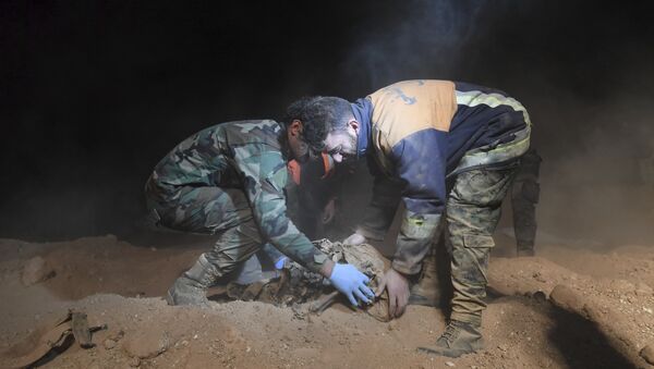 Članovi Sirijskih snaga bezbednosti uklonjaju posmrtne ostatke u otkrivenim masovnim grobnicama za koje se veruje da sadrže tela civila ubijenih od strane islamskih militanata, u selu Vavi blizu grada Rake u Siriji. - Sputnik Srbija