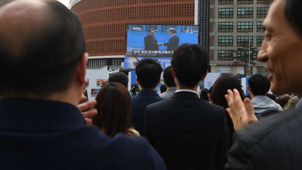 Narod aplaudira dok posmatra prenos uživo rukovanja predsednika Severne i Južne Koreje, Kim Džong Una i Mun Džae Ina - Sputnik Srbija