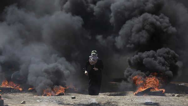 Žena iz Palestine isprd crnog dimom iz gorućih guma tokom protesta u Gazi, ponedeljak, 14. maja 2018. - Sputnik Srbija