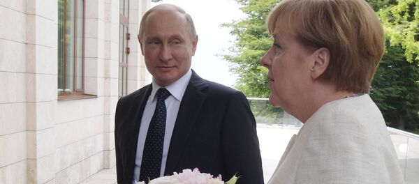 Vladimir Putin sa cvećem sačeako Anglelu Merkel iprkos nesuglasicama. - Sputnik Srbija