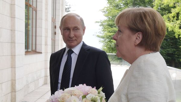 Vladimir Putin sa cvećem sačeako Anglelu Merkel iprkos nesuglasicama. - Sputnik Srbija