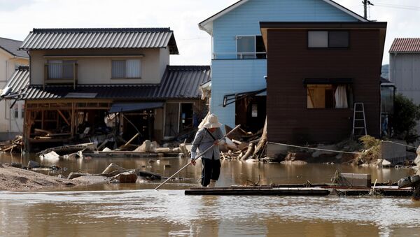 Žena hoda u blizini kuća potopljenih i uništenih u poplavama u japanskom gradu Kurašiki - Sputnik Srbija