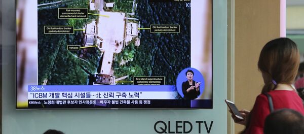 Ljudi gledaju satelitske snimke poligona za lansiranje raketa Sohae u Severnoj Koreji na južnokorejskoj televiziji u Seulu - Sputnik Srbija