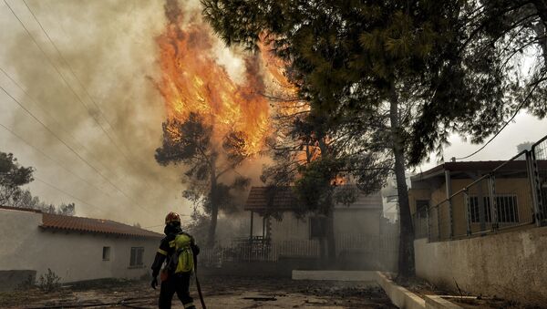 Vatrogasac pokušava da ugasi požar u Kineti u blizini Atine u Grčkoj - Sputnik Srbija