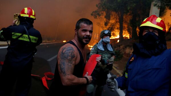 Vatrogasac pokušava da ugasi požar blizini Atine u Grčkoj - Sputnik Srbija
