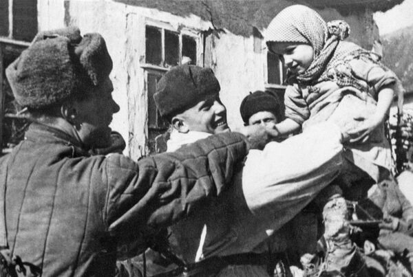 Pripadnici Crvene armije sa lokalnim stanovništvom oslobođenog sela u blizini Kurska 1943. godine za vreme Drugog svetskog rata. - Sputnik Srbija