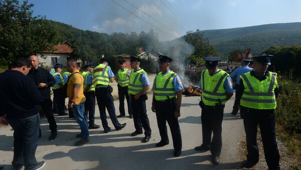 Припадници полиције стоје поред блокаде коју су направили Албанци на путу ка селу Бање на Косову и Метохији - Sputnik Србија