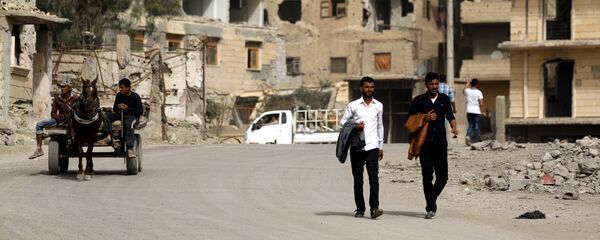 Ljudi prolaze pored ruševina stambenih zgrada u Raki na severu Sirije - Sputnik Srbija