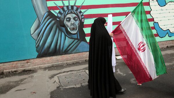 Iranka nosi nacionalnu zastavu dok prolazi pored murala na kojem je prikazana američka Statua slobode - Sputnik Srbija