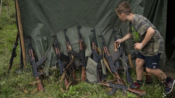 Dečak pored puške AK-47 u kampu u blizini Ternopila, Ukrajina - Sputnik Srbija