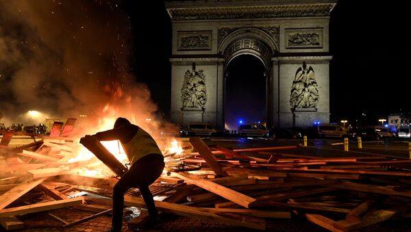 Pripadnik pokreta žuti prsluci dodaje drva na vatru ispred Trijumfalne kapije u Parizu 24. novembra 2018. - Sputnik Srbija
