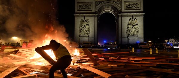 Pripadnik pokreta žuti prsluci dodaje drva na vatru ispred Trijumfalne kapije u Parizu 24. novembra 2018. - Sputnik Srbija