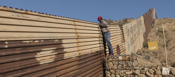 Migrant iz Hondurasa gleda preko ograde na granici između SAD i Meksika Migrant iz Hondurasa gleda preko ograde na granici između SAD i Meksika - Sputnik Srbija