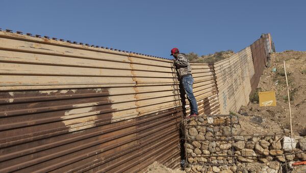 Migrant iz Hondurasa gleda preko ograde na granici između SAD i Meksika - Sputnik Srbija