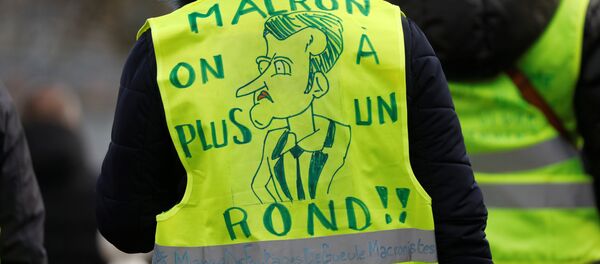 Pripadnik Pokreta Žuti prsluci na protestu. Natpis na prsluku: Makrone, bankrotirali smo. - Sputnik Srbija