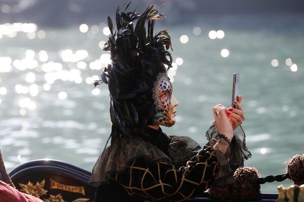 Maskirana žena stoji u gondoli za vreme parade u Veneciji u Veneciji, Italija u nedjelju 17. februara 2019. - Sputnik Srbija