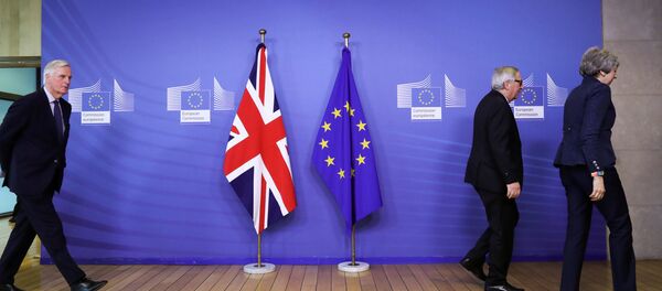 Glavni pregovarač EU za bregzit Mišel Barnije hoda iza Žan Klod Junkera i Tereze Mej u Briselu. Zastave EU i Velike Britanije. - Sputnik Srbija