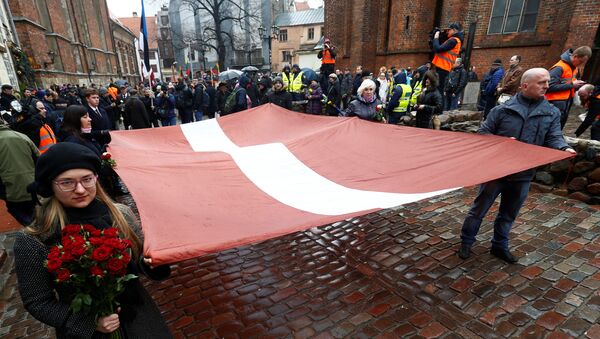 Људи носе заставу на обележавању летонске нацистичке легије Вафен СС у Риги - Sputnik Србија