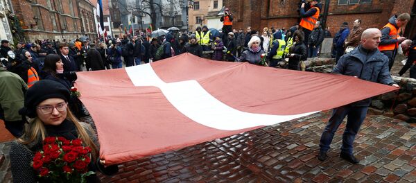 Људи носе заставу на обележавању летонске нацистичке легије Вафен СС у Риги - Sputnik Србија