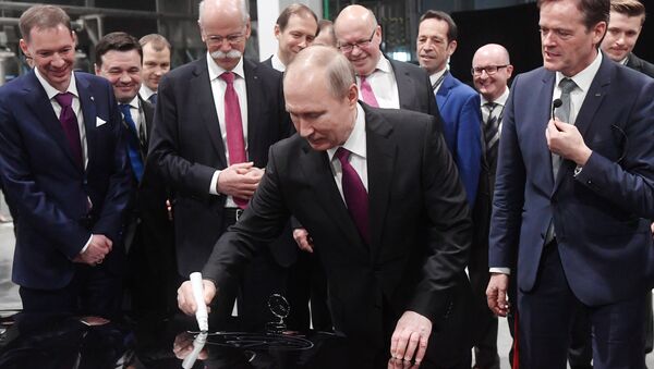 Predsednik Rusije Vladimir Putin potpisuje se na haubi mercedesa - Sputnik Srbija