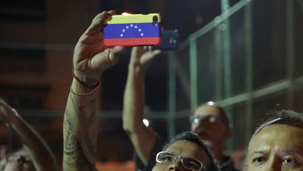 Човек држи мобилни телефон у бојама заставе Венецуеле - Sputnik Србија