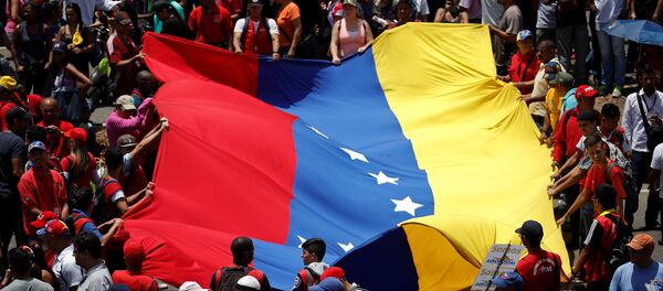Pristalice Nikolasa Madura nose zastavu Venecuele na mitingu u Karakasu Pristalice Nikolasa Madura nose zastavu Venecuele na mitingu u Karakasu - Sputnik Srbija