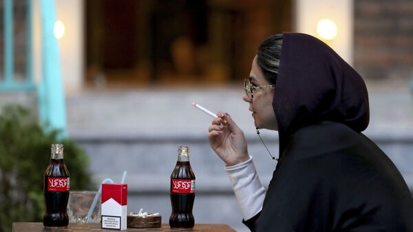 Iranka u jednom teheranskom restoranu puši cigarete Malboro i pije Koka kolu. Onemogućavanje proizvodnje balističkih raketa, smanjivanje iranskog uticaja u regionu i eventualna promena režima u Iranu su tri američka cilja, prema Bisenićevim rečima  - Sputnik Srbija