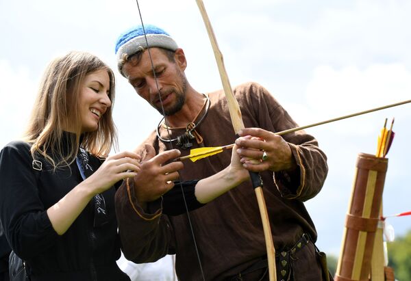 Учесник фестивала показује дами како да користи лук и стрелу. - Sputnik Србија