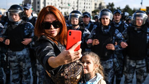 Жена са дететом се фотографише испред кордона полиције на неодобреном протесту у Москви - Sputnik Србија
