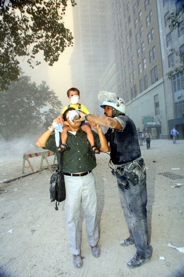 Policajac pomaže u evakuaciji ljudi iz Svetskog trgovinskog centra 11. septembra 2001. - Sputnik Srbija