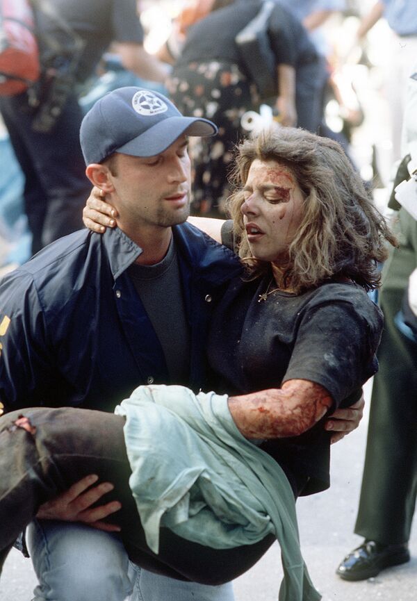 Američki savezni maršal Dominik Gvadagnoli pomaže ranjenoj ženi nakon terorističkog napada 11. septembra 2001. u Njujorku. - Sputnik Srbija