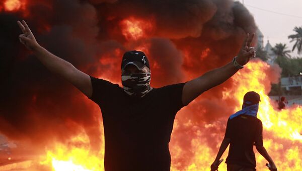 Demonstrant u Bagdadu stoji sa uzdignutim rukama u znak pobede.  - Sputnik Srbija