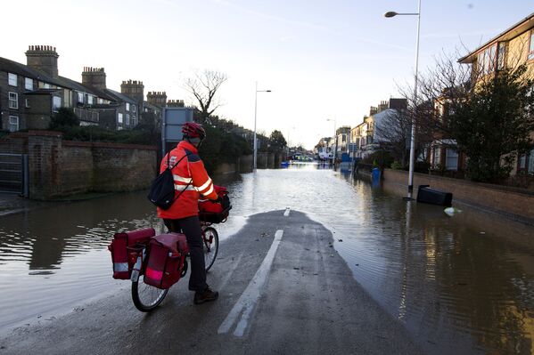 Poštar se zaustavlja i gleda poplavljenu ulicu u Lovestoftu, na istoku Engleske, 6. decembra 2013. godine, nakon što je plimni nalet pogodio lokacije duž istočne obale Britanije.
 - Sputnik Srbija