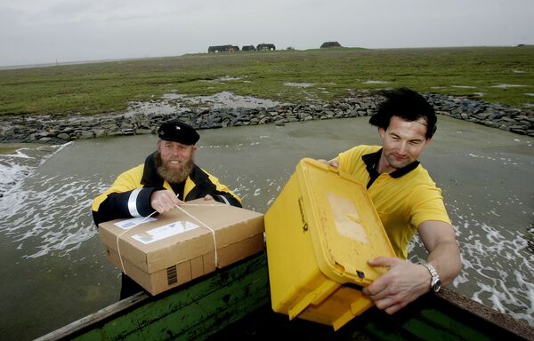Nemački skiper sa najdaljeg severa Fide Nisen i njegov kolega Andreas Oberauer, za koga se kaže da je najseverniji njemački poštar, donose pakete i pisma stanovnicima malog ostrva Groede u Severnom moru u utorak, 5. decembra 2006. - Sputnik Srbija