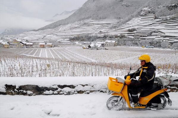 Poštar na motociklu vozi kroz sveži sneg u Ejglu, kanton Vaud u zapadnoj Švajcarskoj, 24. novembra 2008. godine. - Sputnik Srbija