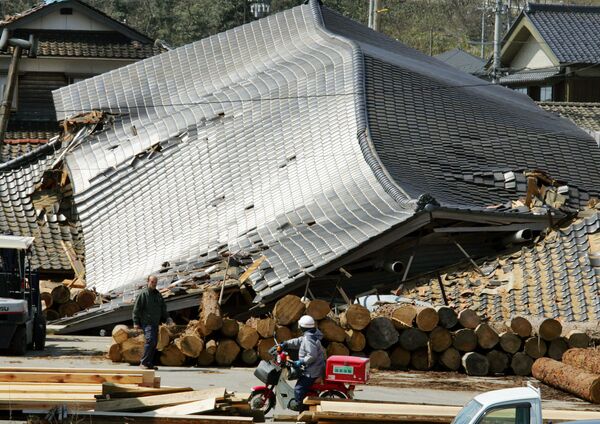 Poštar na motociklu pored srušenih zgrada na Vajima, jednom od područja koja su najteže pogođena u prefekturi Išikava (država), severni Japan, 26. mart 2007. - Sputnik Srbija