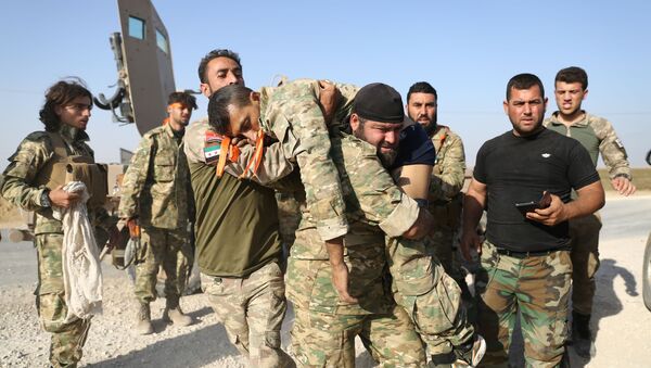 Proturski borci u Siriji evakuišu ranjenika posle sukoba sa Kurdima. - Sputnik Srbija