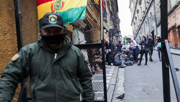 Припадник снага безбедности Боливије стоји поред присталица опозиције током сукоба на протесту у Ла Пазу - Sputnik Србија
