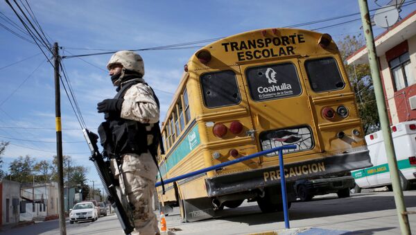 Војни полицајац испред изрешетаног школског аутобуса после сукоба са нарко-картелом на северу Мексика. - Sputnik Србија